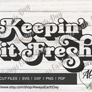 May include: A black and white graphic design with the text "Keepin' it Fresh" in a retro style font. The design is on a white wood background with a small logo in the bottom right corner that says "Always Earth Day" with the initials "AED".