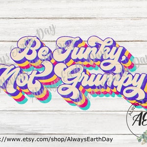 Peut inclure: Un design graphique rétro avec le texte "Be Funky, Not Grumpy" dans un schéma de couleurs arc-en-ciel. Le texte est en 3D avec un aspect vintage et vieilli. Le design est sur un fond en bois blanc.