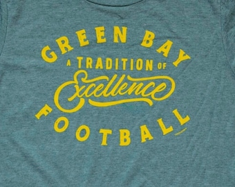 Könnte beinhalten: Grünes T-Shirt mit einer gelben Grafik, auf der "Green Bay A Tradition of Excellence Football" steht.