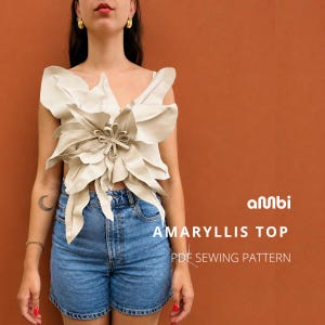 May include: A cream-colored Amaryllis top with a large, flower-like design. The top is paired with denim shorts. The text "AMARYLLIS TOP PDF SEWING PATTERN" is visible on the image.