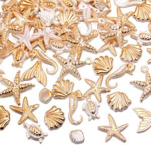 May include: A collection of gold and silver-toned seashell charms, including starfish, seahorses, and scallop shells. The charms are scattered across a white surface, creating a nautical theme. These decorative charms are ideal for jewelry making or craft projects.