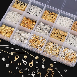 Peut inclure: Un organisateur en plastique transparent rempli de fournitures pour la fabrication de bijoux. Les compartiments contiennent des perles de couleur or et argent, des fermoirs, des clous à tête et d'autres petits composants. Les articles sont disposés avec soin, présentant une variété de formes et de tailles pour l'artisanat.