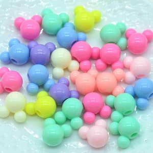 May include: Assortment of pastel coloured plastic beads shaped like Mickey Mouse heads. The beads are perfect for jewellery making, crafts, and other creative projects.