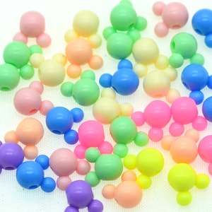 May include: A collection of colorful plastic beads shaped like Mickey Mouse heads. The beads are in various pastel colors, including pink, blue, green, yellow, and purple.