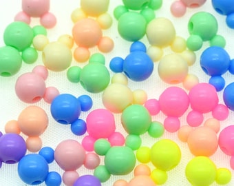May include: A collection of colorful plastic beads shaped like Mickey Mouse heads. The beads are in various pastel colors, including pink, blue, green, yellow, and purple.