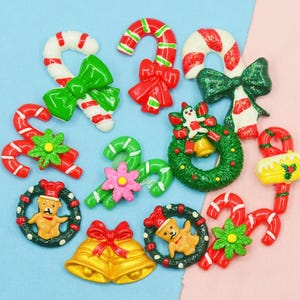 May include: Assortment of Christmas-themed resin embellishments, including candy canes, wreaths, bells, and bears. The embellishments are in various colors, including red, green, white, and gold.