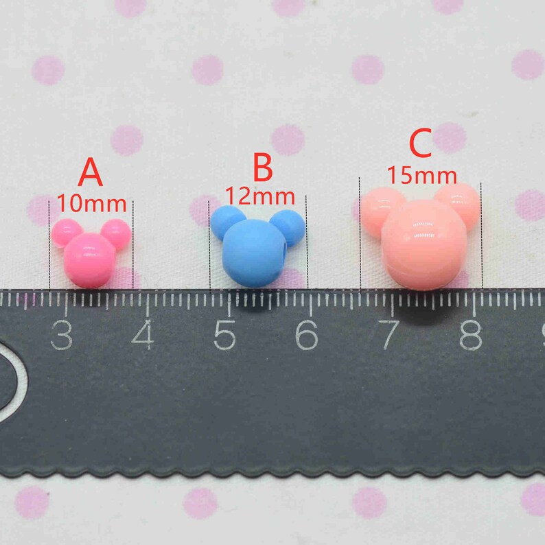 May include: Three plastic Mickey Mouse head beads in pink, blue, and light pink. The beads are 10mm, 12mm, and 15mm in size.
