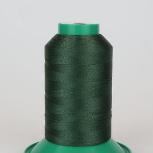 Puede incluir: Una bobina de hilo verde oscuro en una bobina de plástico verde.