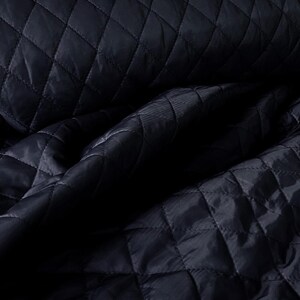 May include: Close-up of a dark blue quilted fabric with a diamond pattern. The fabric is soft and textured, with a subtle sheen.