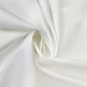 May include: White fabric with a smooth, silky texture. The fabric is folded and draped, creating soft folds and curves.
