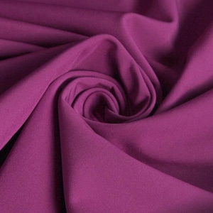 Peut inclure: Gros plan sur un tissu violet foncé à la texture douce et lisse. Le tissu est plié et drapé, créant un aspect luxueux et élégant.