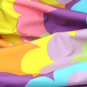 May include: A colorful fabric with a pattern of overlapping, abstract shapes in shades of pink, purple, yellow, orange, and blue.