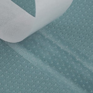 Peut inclure: Gros plan sur une surface texturée de couleur sarcelle avec une bande adhésive blanche qui se décolle. La surface présente un motif subtil de points, et l'adhésif est partiellement soulevé.