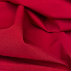 May include: Close-up of a vibrant red fabric with soft folds and a subtle texture. The material appears to be a smooth, flowing textile, possibly suitable for apparel or home decor projects. The rich color suggests a luxurious feel.
