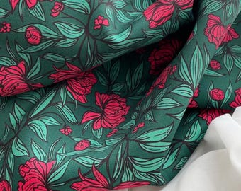 May include: Dark green fabric with a repeating floral pattern. The design features large, stylized red flowers and green leaves with black outlines. The fabric is draped over a white surface.