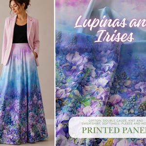 Pode incluir: Uma mulher usando um blazer rosa claro e uma saia longa com estampa floral. A saia apresenta um design em aquarela com flores azuis, roxas e brancas. A imagem também mostra um painel impresso com o texto "Lupinas and Irises".