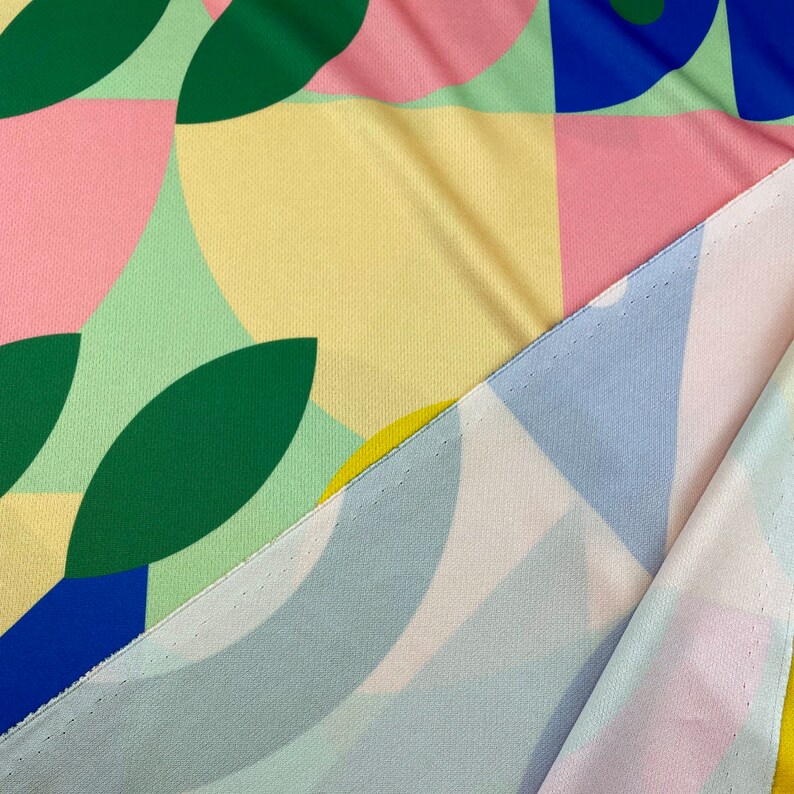 K&ouml;nnte beinhalten: Zwei Stoffst&uuml;cke mit geometrischen Mustern. Ein St&uuml;ck ist gr&uuml;n, gelb, rosa und blau mit Kreisen und Bl&auml;ttern. Das andere St&uuml;ck ist hellblau, wei&szlig; und rosa mit geschwungenen Formen.