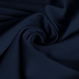 Puede incluir: Primer plano de una tela azul oscuro con una textura lisa. La tela está doblada y drapeada, creando pliegues y curvas suaves.