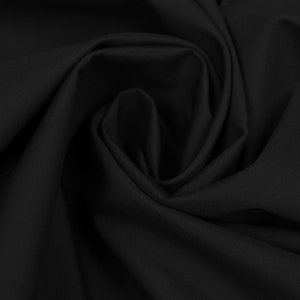 May include: A close-up shot of black fabric with soft folds and shadows. The fabric appears to be smooth and possibly a lightweight material, with a subtle sheen. The dark color creates a dramatic effect.