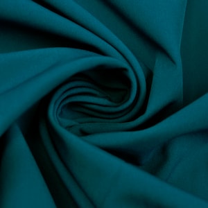 May include: Close-up of teal fabric with soft folds and a swirling pattern. The fabric has a smooth texture and a deep, rich colour, creating a sense of depth and movement. The material appears to be a lightweight textile, suitable for apparel or home decor.