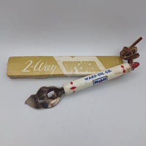 May include: Vintage 2-Way bottle opener with a white handle featuring red diamond accents and the Mobil logo. The opener is paired with its original gold-colored box, which reads "2-Way OPENER". A leather loop is attached to the end of the opener.