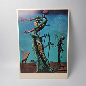 May include: Surrealist art print featuring a tall, green figure with outstretched arms, a purple head covering, and a series of small, rectangular objects. A giraffe engulfed in flames and another figure are also depicted against a blue backdrop.