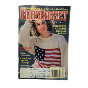 May include: The July 1991 issue of The Workbasket and Home Arts Magazine features a person wearing a cream-colored long-sleeve pullover sweater with a prominent American flag design on the front, including red and white stripes and white stars.