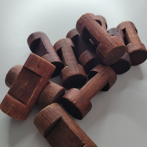 May include: A group of wooden puzzle pieces in various shapes and sizes. The pieces are a dark brown color and have a smooth, polished finish.