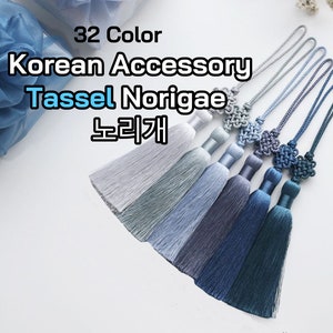 Könnte beinhalten: Ein Set mit 32 farbigen koreanischen Quasten-Norigae, auch bekannt als "Norigae", in Blautönen. Die Quasten sind aus Seide gefertigt und mit einem traditionellen koreanischen Knoten verziert. Die Norigae sind ein traditionelles koreanisches Accessoire, das zum Hanbok, dem traditionellen koreanischen Kleid, getragen wird.