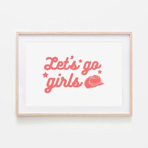 May include: A framed print with the text "Let's go girls" in pink lettering with a pink cowboy hat graphic. The print is in a light wood frame.