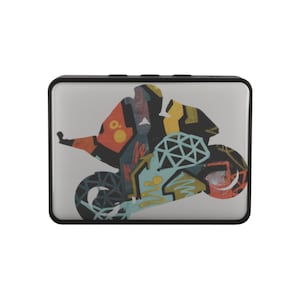 Puede incluir: Un pequeño altavoz rectangular gris con un borde negro. El altavoz tiene un gráfico colorido de una motocicleta con un conductor.