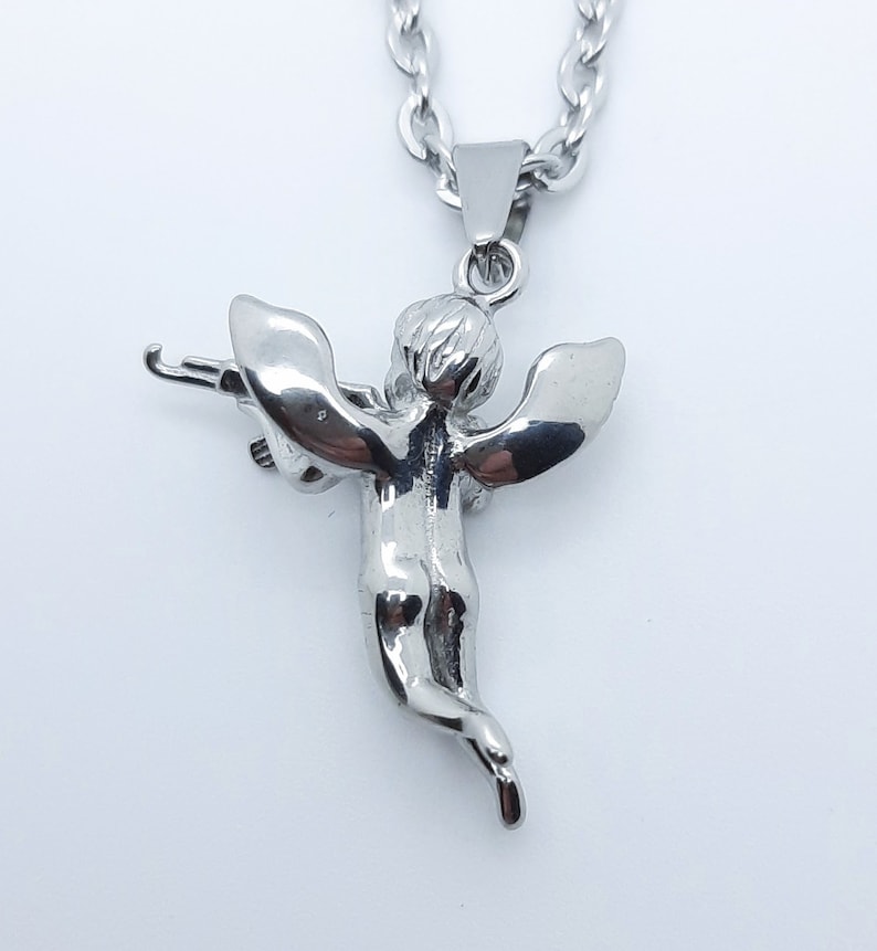 Pu&ograve; includere: Collana con catena d'argento con un ciondolo a forma di cherubino che tiene un arco e una freccia. Il cherubino &egrave; dettagliato e ha le ali.