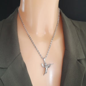 Pu&ograve; includere: Una collana con catena d'argento con un ciondolo a forma di angelo che tiene una pistola.
