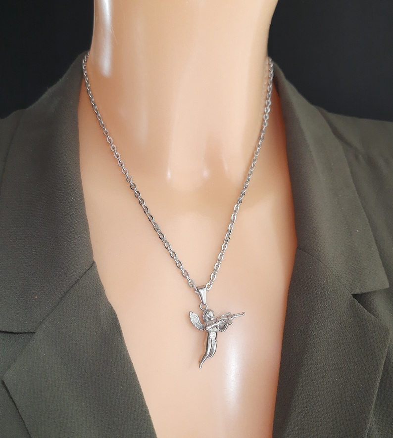 Pu&ograve; includere: Una collana con catena d'argento con un ciondolo a forma di angelo che tiene una pistola.
