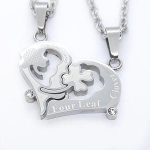 May include: Two silver necklaces with a heart-shaped pendant that is split into two pieces. One piece has a four-leaf clover design and the text "Four Leaf Clover" and the other piece has a clover design and the text "Clover".