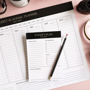 Könnte beinhalten: Ein schwarz-weißer wöchentlicher akademischer Planer mit einer schwarzen Kopfzeile, auf der "Weekly Academic Planner" und "Basic Hexes" steht. Der Planer hat Spalten für jeden Tag der Woche mit Platz zum Eintragen von Daten und Aufgaben. Ein kleiner schwarz-weißer Notizblock mit dem Text "Today's Plan" und "Basic Hexes" liegt auf dem Planer. Der Notizblock hat Abschnitte für "Things to do", "Top Priorities", "Goals" und "Notes & Scribbles".