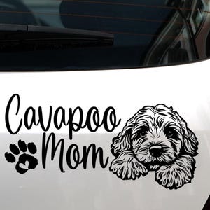 May include: A black and white decal featuring the text "Cavapoo Mom" with a paw print and heart design. The decal also includes a detailed illustration of a Cavapoo dog.