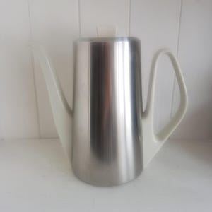 Könnte beinhalten: Eine Kaffeekanne aus Edelstahl mit weißem Deckel und Griff. Die Kanne hat ein schlankes, modernes Design.