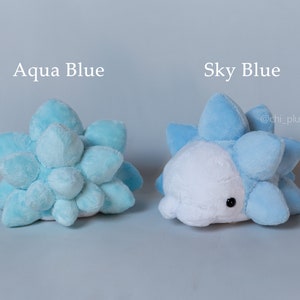 Puede incluir: Dos peluches con forma de criatura azul y espinosa. El peluche de la izquierda es azul aguamarina y el de la derecha es azul cielo. El texto "Aqua Blue" est&aacute; encima del peluche de la izquierda y el texto "Sky Blue" est&aacute; encima del peluche de la derecha. El texto "@chi_plush" est&aacute; debajo del peluche de la derecha.