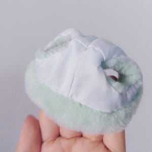 May include: A light green faux fur trim collar with a white lining. The collar is designed to be worn around the neck.