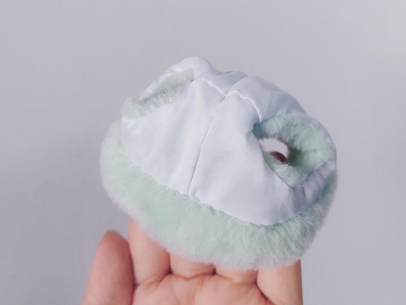 May include: A light green faux fur trim collar with a white lining. The collar is designed to be worn around the neck.