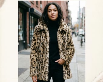 May include: A faux fur coat with a brown and black leopard print pattern, featuring a wide collar and long sleeves. The text Faux Fur Coat Leopard and Luxurious warmth, timeless style, for cold-weather days. is visible on the image.