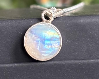 May include: A silver chain necklace with a round, iridescent moonstone pendant.
