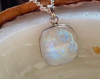 May include: A silver chain necklace with a white moonstone pendant. The moonstone is a rectangular shape with a pearlescent sheen.
