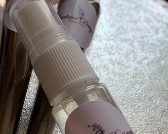 May include: Clear spray bottles with white tops and labels that read "Radiant Design Henna Artist." Several henna cones are visible. The bottles are on a silver tray. The background is a solid red color.