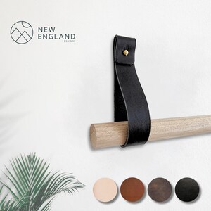 May include: Black leather strap with a brass screw, attached to a wooden dowel rod.  The strap is used to hang a towel bar on a wall.  The strap is available in five colors:  light pink, brown, dark brown, black, and gray.