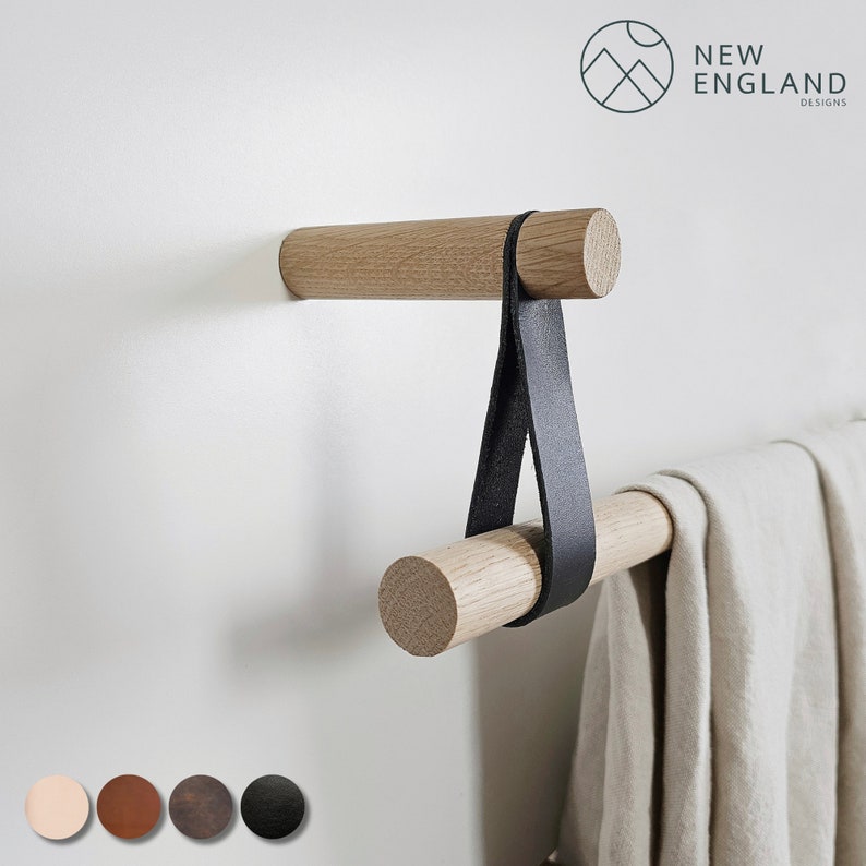 Puede incluir: Un toallero de madera con una correa de cuero negro colgando de &eacute;l. El toallero est&aacute; montado en una pared blanca. El toallero est&aacute; hecho de madera natural y tiene un dise&ntilde;o simple. La correa est&aacute; hecha de cuero de alta calidad y tiene un dise&ntilde;o simple y elegante. El toallero es perfecto para agregar un toque de encanto r&uacute;stico a cualquier ba&ntilde;o o cocina.