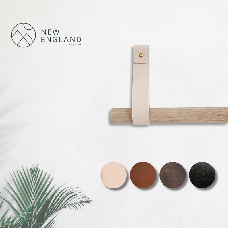 May include: A wooden dowel rod with a leather strap attached to the wall. The strap has a brass rivet. The strap is available in five colors: blush, brown, dark brown, black, and gray.