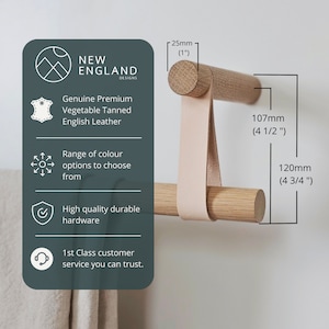 Puede incluir: Un toallero de madera con una correa de cuero, que mide 120 mm de largo y 107 mm de alto. La barra es de madera natural y tiene un aspecto r&uacute;stico. La correa de cuero es de color marr&oacute;n claro y est&aacute; unida a la barra con dos tornillos de metal. La barra est&aacute; montada en una pared blanca.
