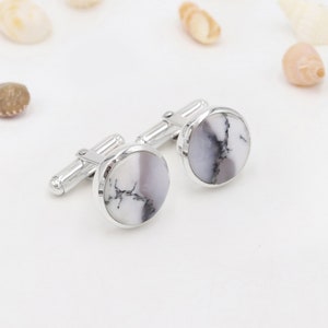 Peut inclure: Une paire de boutons de manchette en argent avec des incrustations rondes en agate blanche et grise.